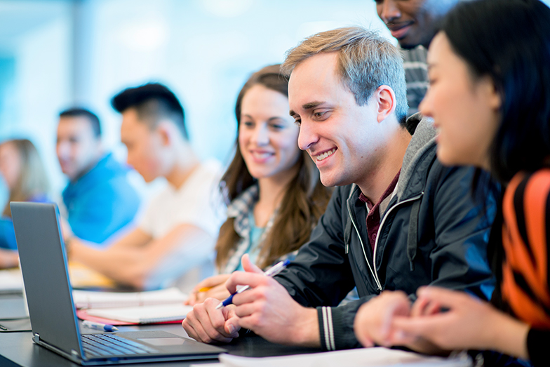 Symbolbild Bachelor-Studiengang Wirtschaftsinformatik: Studierende sitzen in einem Seminarraum und schauen auf einen Laptop.