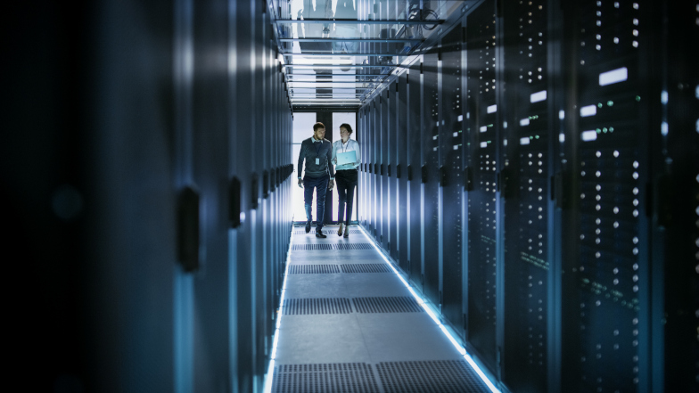 Symbolbild: Zwei Personen laufen in einem Rechenzentrum zwischen den Serverschränken. (Quelle: Getty Images / gorodenkoff) Symbolbild: Zwei Personen laufen in einem Rechenzentrum zwischen den Serverschränken.