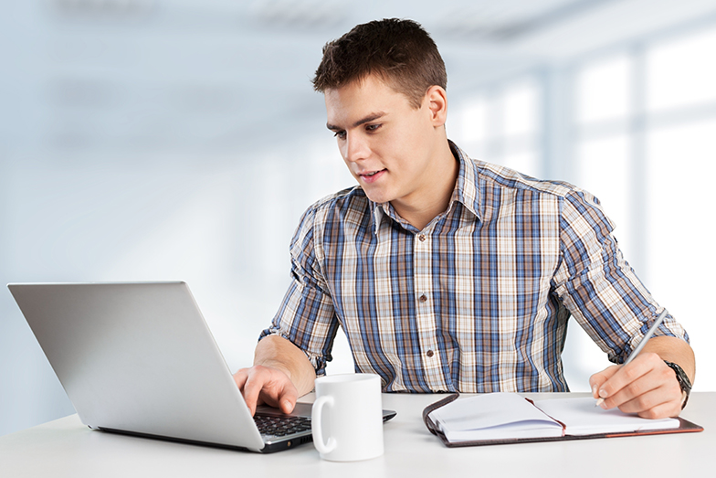 Symbolbild: Junger Mann sitzt am Schreibtisch und tippt auf Tastatur (Quelle: 123RF / olegdudko) Symbolbild: Junger Mann sitzt am Schreibtisch und tippt auf Tastatur