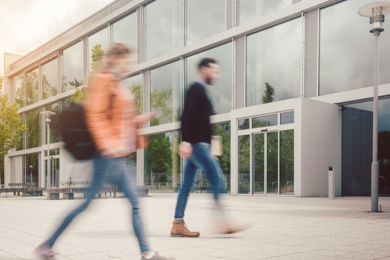 Symbolbild Studium Verwaltungsinformatik: Zwei Studierende laufen in ein Gebäude. (Quelle: Adobe Stock / Kzenon) Symbolbild Studium Verwaltungsinformatik: Zwei Studierende laufen in ein Gebäude.