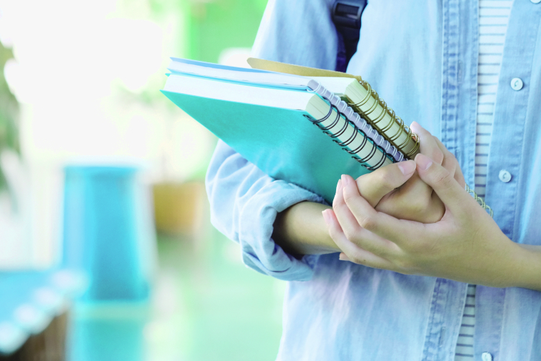 Symbolbild Start ITM-Studium. Vor dem Hintergrund eines Campus-Umfelds Hände einer jungen Studentin mit Schreibblocks. (Quelle: Adobe Stock / mangpor2004) Symbolbild Start ITM-Studium. Vor dem Hintergrund eines Campus-Umfelds Hände einer jungen Studentin mit Schreibblocks.
